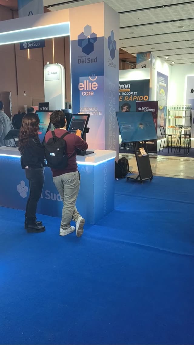 Dos visitantes usando los tótems en el stand de Droguería Del Sud en Expo Esencia